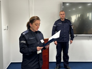Zdjęcie przedstawia umundurowaną policjantkę. W tle Komendant Miejski Policji w Sosnowcu.