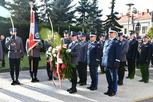 Przedstawiciele kierownictwa Policji idą w stronę pomnika z kwiatami