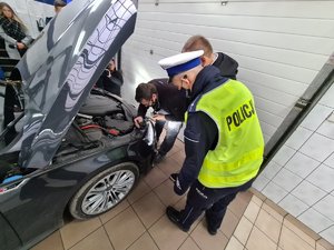 Policjant i pracownik stacji kontroli pojazdów sprawdzają światła w pojeździe