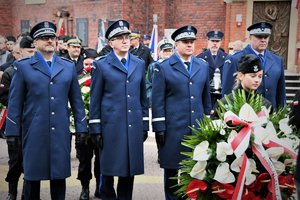 Kolorowe zdjęcie. Policyjna delegacja składa kwiaty.