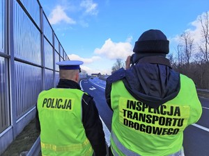 Widoczni policjanci i uczestnicy działań podczas kontroli autokarów przy autostradzie DK 81 w Ochabach Małych (zjazd na Wiślicę)