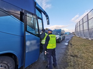 Widoczni policjanci i uczestnicy działań podczas kontroli autokarów przy autostradzie DK 81 w Ochabach Małych (zjazd na Wiślicę)