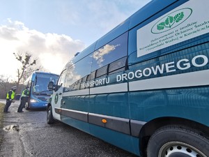 Widoczni policjanci i uczestnicy działań podczas kontroli autokarów przy autostradzie DK 81 w Ochabach Małych (zjazd na Wiślicę)