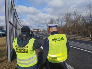 Widoczni policjanci i uczestnicy działań podczas kontroli autokarów przy autostradzie DK 81 w Ochabach Małych (zjazd na Wiślicę)