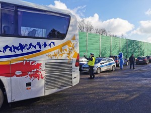 Widoczni policjanci i uczestnicy działań podczas kontroli autokarów przy autostradzie DK 81 w Ochabach Małych (zjazd na Wiślicę)