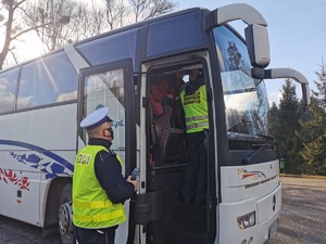 Widoczni policjanci i uczestnicy działań podczas kontroli autokarów przy autostradzie DK 81 w Ochabach Małych (zjazd na Wiślicę)