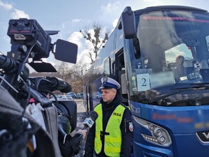 Widoczni policjanci i uczestnicy działań podczas kontroli autokarów przy autostradzie DK 81 w Ochabach Małych (zjazd na Wiślicę)