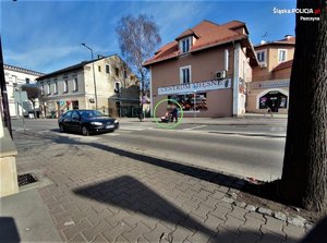 Samochód przejeżdża przez przejście przed którym oczekuje pieszy z wózkiem