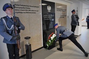 Widoczni umundurowani policjanci podczas składania kwiatów przed Tablicą Pamięci w KWP w Katowicach