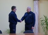 Zdjęcie wykonane w sali konferencyjnej Komendy Miejskiej Policji w Sosnowcu przedstawia insp. Dominika Łączyka - Komendanta Miejskiego Policji w Sosnowcu gratulującego podinsp. Mariuszowi Łabędzkiemu.