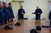 Zdjęcie wykonane w sali konferencyjnej Komendy Miejskiej Policji w Sosnowcu przestawiające insp. Dominika Łączyka - Komendanta Miejskiego Policji w Sosnowcu, podinsp. Mariusza Łabędzkiego - Naczelnika Wydziału Prewencji Komendy Miejskiej Policji w Sosnowcu oraz kadrę kierowniczą Komendy Miejskiej Policji w Sosnowcu.