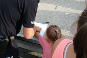 policjant pomaga dziewczynce pobrać odcisk dłoni ( daktyloskopia)