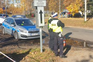 policjanci przy radiowozie przed cmentarzem