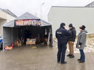 policjanci rozmawiają z ludźmi przed punktem sprzedaży materiałów pirotechnicznych