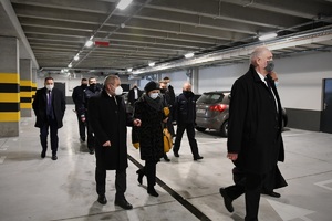 Zdjęcie kolorowe. Widoczni goście uroczystego otwarcia oraz policjanci podczas oprowadzania po budynku komendy