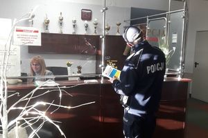 policjant przekazuje ulotki do recepcji hotelu