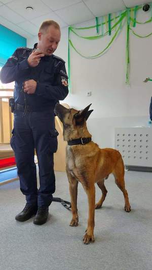 Zdjęcie przedstawia policjanta z psem służbowym.