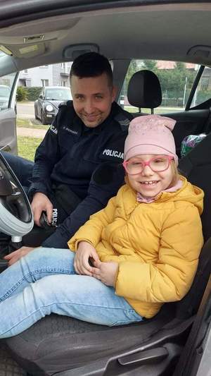 Zdjęcie przedstawia policjanta i dziecko w radiowozie.