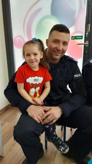 Zdjęcie przedstawia policjanta z dzieckiem.