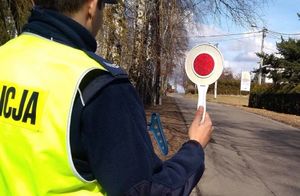 Zdjęcie przedstawia policjanta z tarczą do zatrzymywania pojazdów.