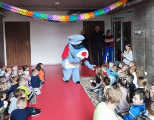 Zdjęcie przedstawia maskotkę policyjną - Sznupka -  w gronie przedszkolaków.