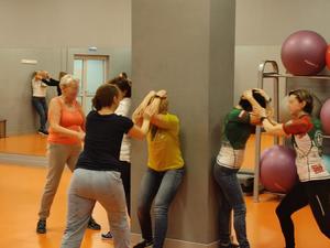 Zdjęcie przedstawia kobiety w trakcie ćwiczeń na sali gimnastycznej.