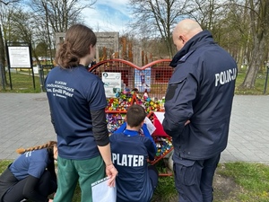 Zdjęcie przedstawia uczniów - uczestników zabawy na jednym z punktów biegu. W tle umundurowany policjant.