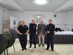 Zdjęcie przedstawia umundurowanych policjantów przemawiających do uczestników spotkania.