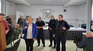 Zdjęcie przedstawia umundurowanych policjantów przemawiających do uczestników spotkania.