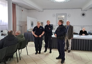 Zdjęcie przedstawia umundurowanych policjantów przemawiających do uczestników spotkania.