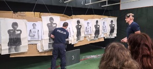 Zdjęcie przedstawia uczniów i instruktora na strzelnicy.