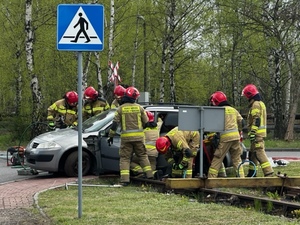 Zdjęcie przedstawia strażaków na tle samochodu.
