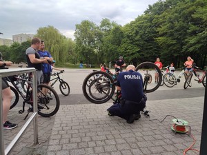 Zdjęcie przedstawia umundurowanego policjanta znakującego rower.