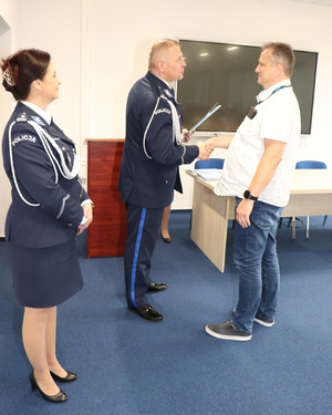 Zdjęcie przedstawia Komendanta Miejskiego Policji w Sosnowcu oraz Zastępcę Komendanta Miejskiego Policji w Sosnowcu gratulujących pracownikowi.