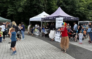 Zdjęcie przedstawia kobietę puszczającą bańki mydlane. W tle uczestnicy Festynu.