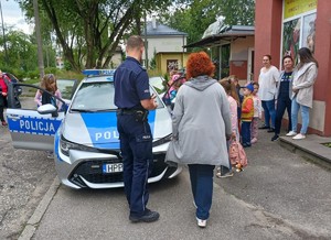 Zdjęcie przedstawia umundurowanego policjanta z dziećmi.