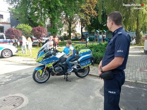 Zdjęcie przedstawia dzieci przy motocyklu służbowym oraz umundurowanego policjanta.