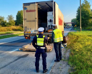 Zdjęcie przedstawia dwóch umundurowanych policjantów stojących przy samochodzie.