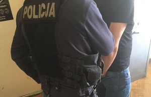 Zdjęcie przedstawia policjanta oraz mężczyznę w kajdankach.