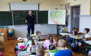 Zdjęcie przedstawia umundurowanego policjanta w klasie.