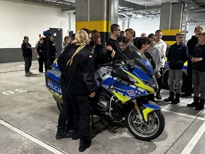 Zdjęcie przedstawia młodzież przy motocyklu służbowym.