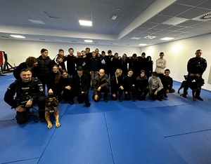 Zdjęcie przedstawia grupę uczniów oraz dwóch umundurowanych policjantów z psami służbowymi.