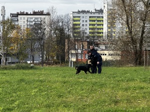 Zdjęcie przedstawia dwóch umundurowanych policjantów z psem służbowym.