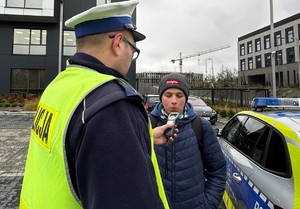 Zdjęcie przedstawia mężczyznę badanego przez umundurowanego policjanta.