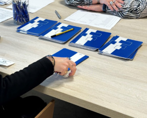 Zdjęcie przedstawia zeszyty oraz długopisy leżące na stole.
