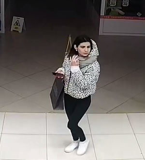 Zdjęcie przedstawia młodą kobietę z ciemnymi włosami na terenie sklepu.