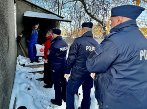 Zdjęcie przedstawia umundurowanych policjantów oraz księdza odwiedzających osobę potrzebującą.