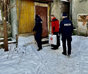 Zdjęcie przedstawia umundurowanych policjantów oraz księdza wchodzących do pomieszczenia.