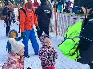 Zdjęcie przedstawia policjantów na stoku narciarskim oraz dzieci.