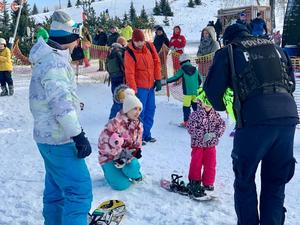 Zdjęcie przedstawia policjantów na stoku narciarskim wręczających dzieciom odblaski.
